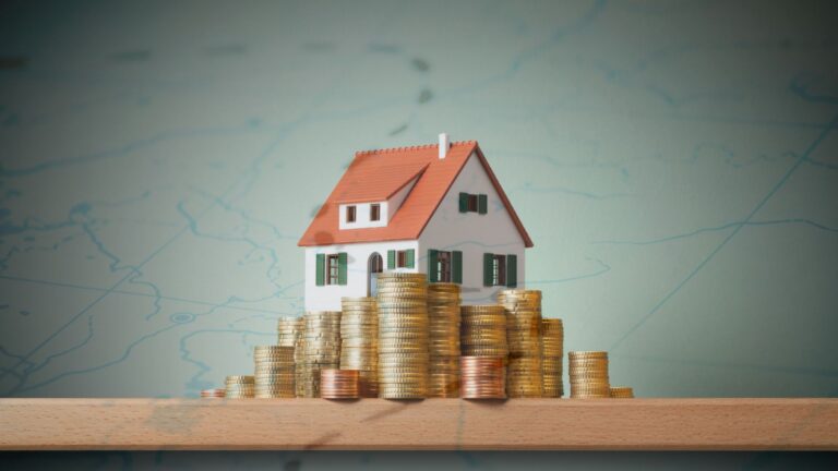 Model house sitting on stacks of coins