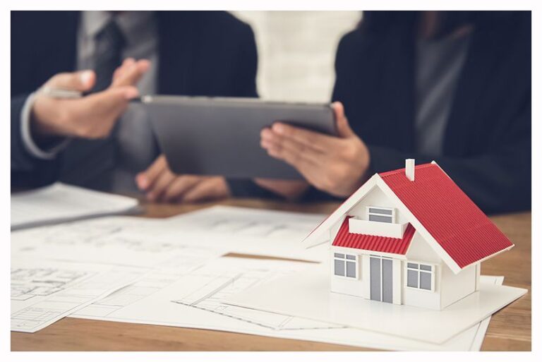 Model house on floor plans while two people review a tablet