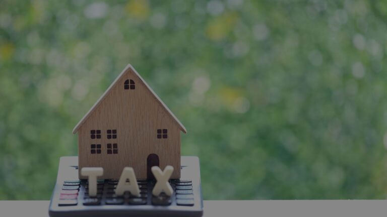 Wooden model house on a calculator with the letters TAX