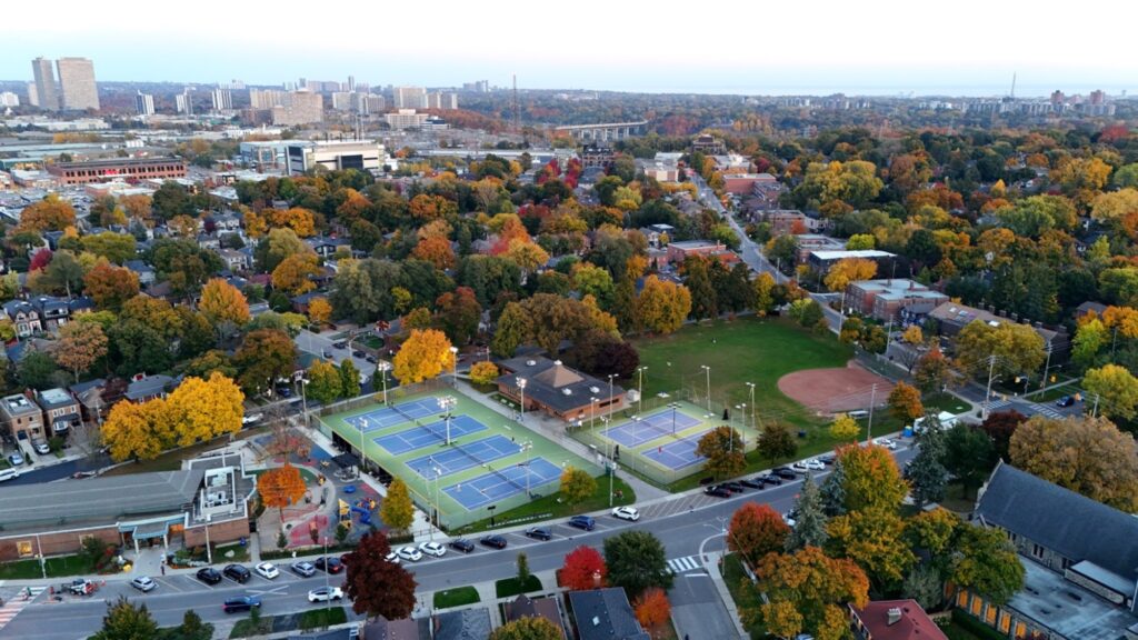 Trace Manes Park and the Leaside homes around it at dusk in fall, the downtown skyline beyond, seen from above