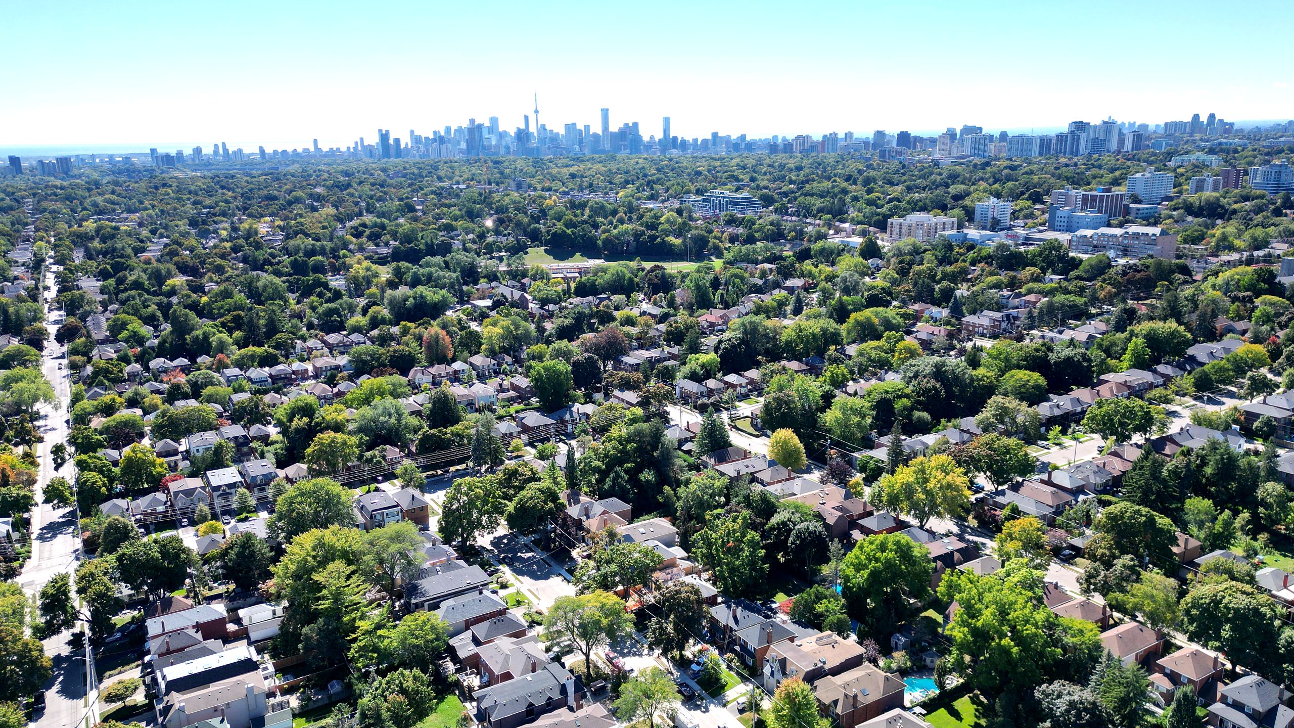 A drone view over North Leaside homes and early-fall trees toward the downtown Toronto skyline, September 2022