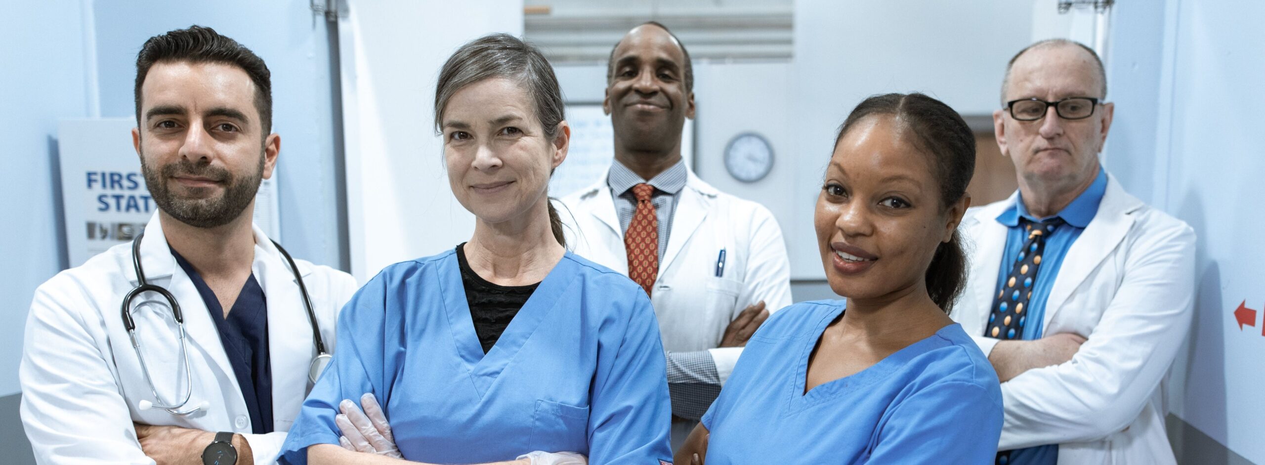 Group of doctors and nurses standing with arms crossed in a hospital hallway